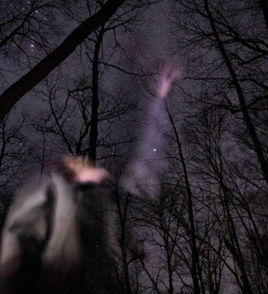 Photo of student studying night sky in winter woods